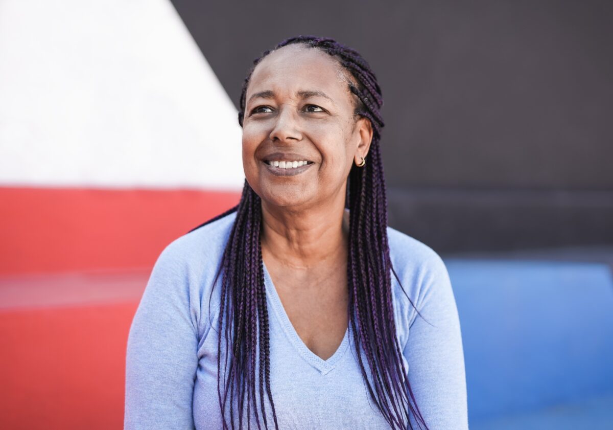 Beautiful african senior woman sitting in front of colorful background